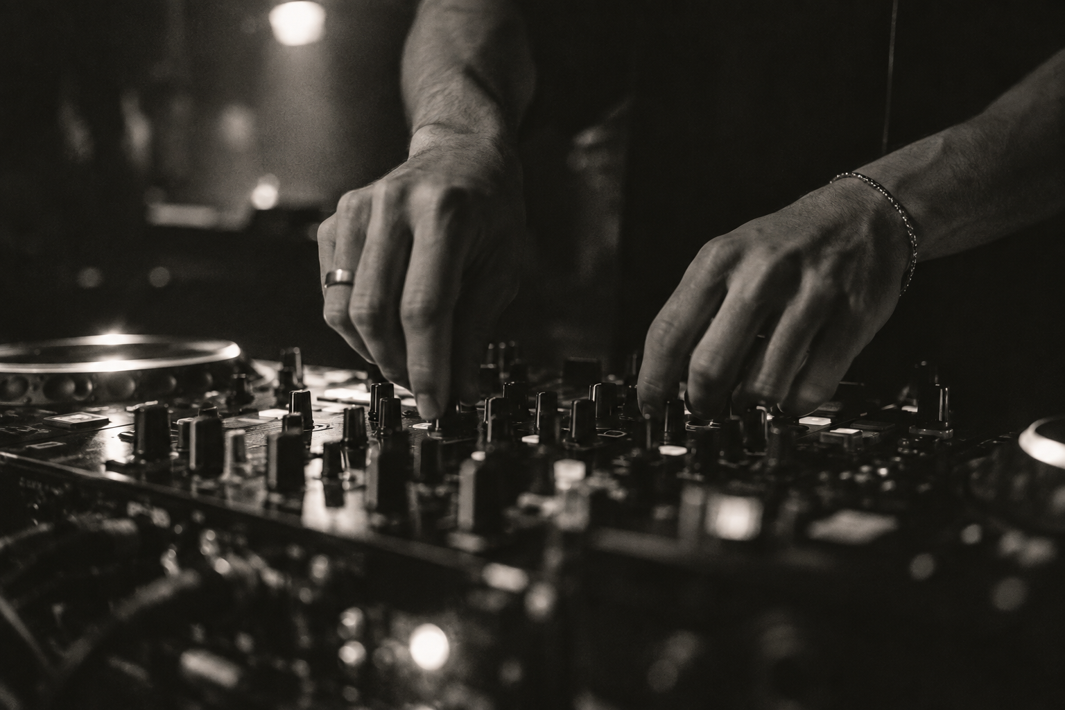 Hands working the mixer in a DJ booth
